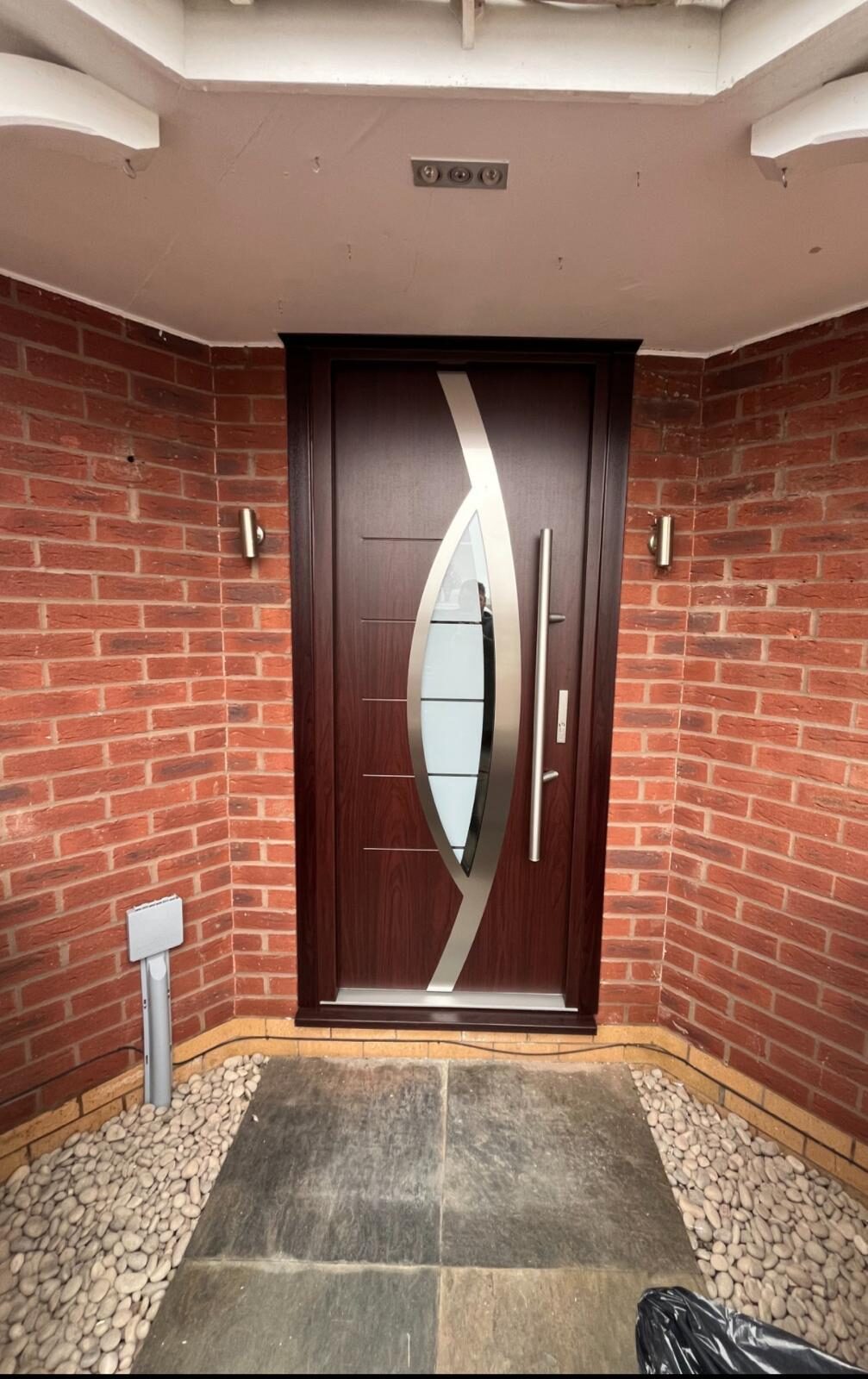 Rosewood composite front door with a curved brushed steel feature panel