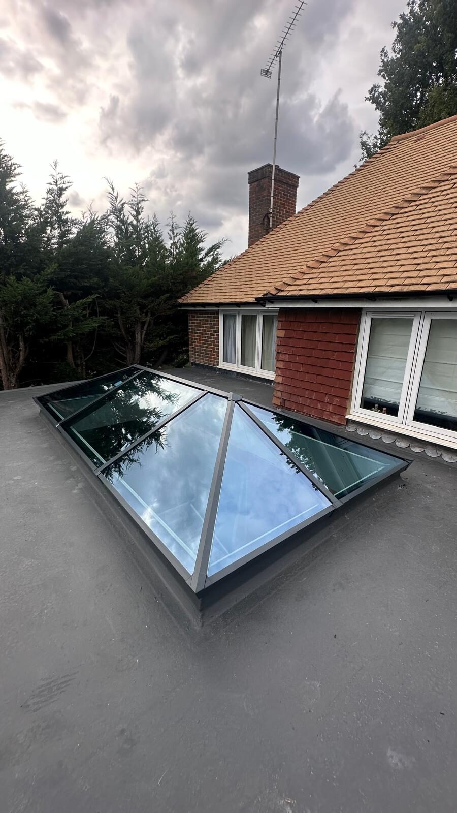 Aluminium roof lantern on a flat roof beside a tiled pitched roof