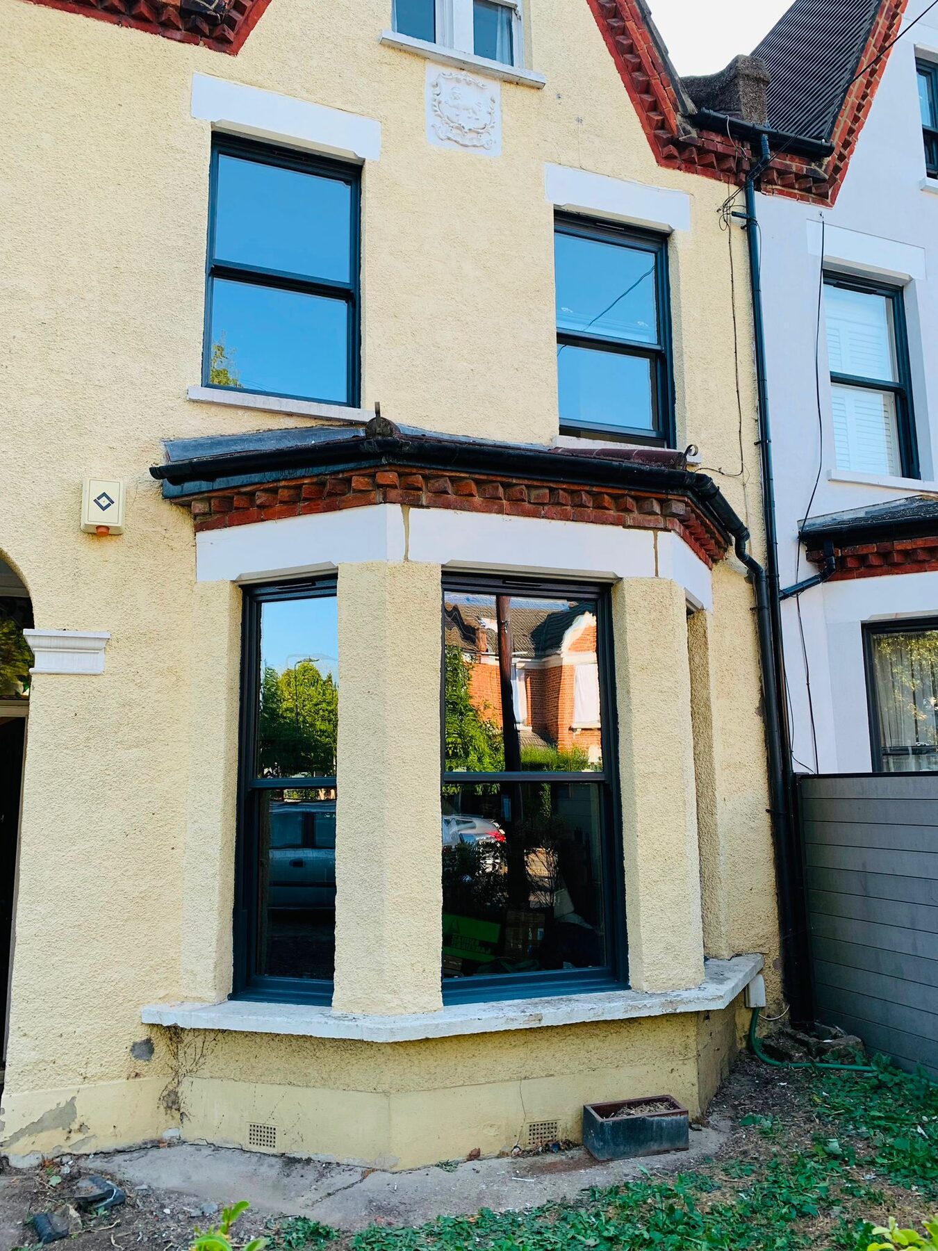 Dark grey sliding sash windows on a period terraced bay